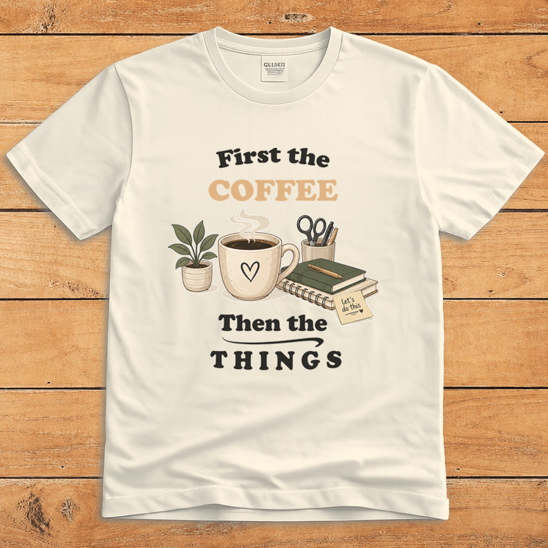 Natural-colored coffee T-shirt with a steaming mug and the words “First the Coffee, Then the Things”