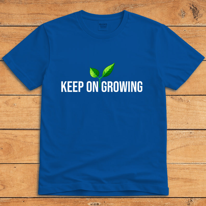 Royal blue plant lover T-shirt featuring a green sprout and the words “Keep on Growing”