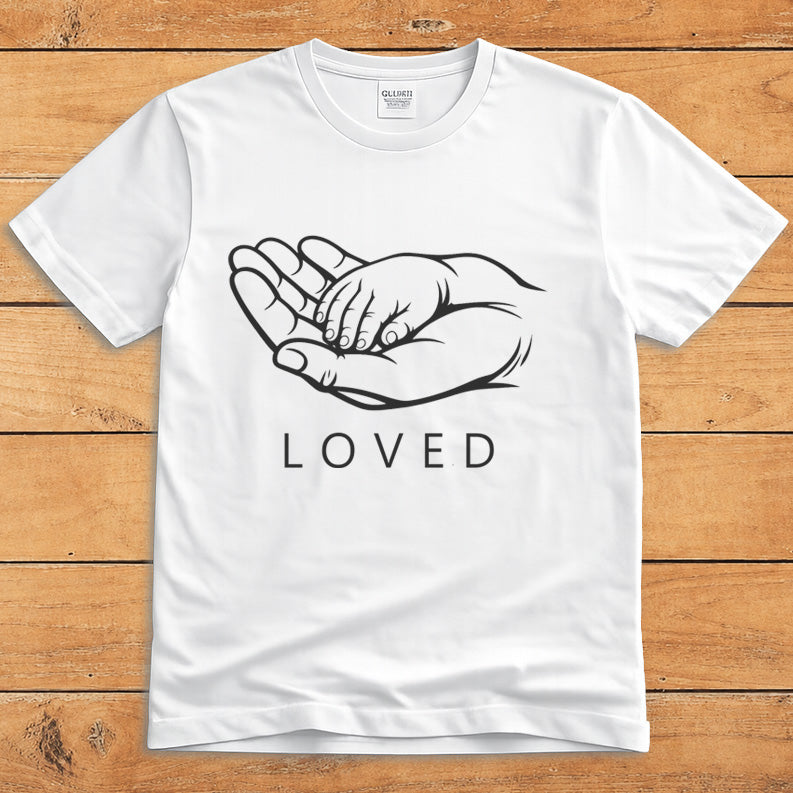 White parent T-shirt showing a grown-up holding a child’s hand alongside the word “LOVED”
