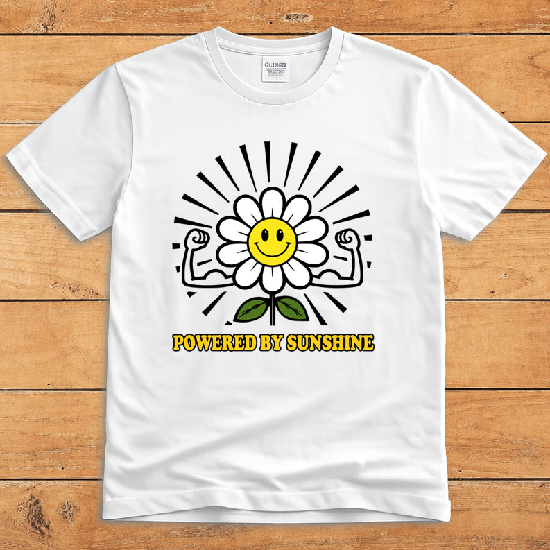 White sunshine T-shirt featuring a smiling daisy flexing its arms and the words “Powered by Sunshine”